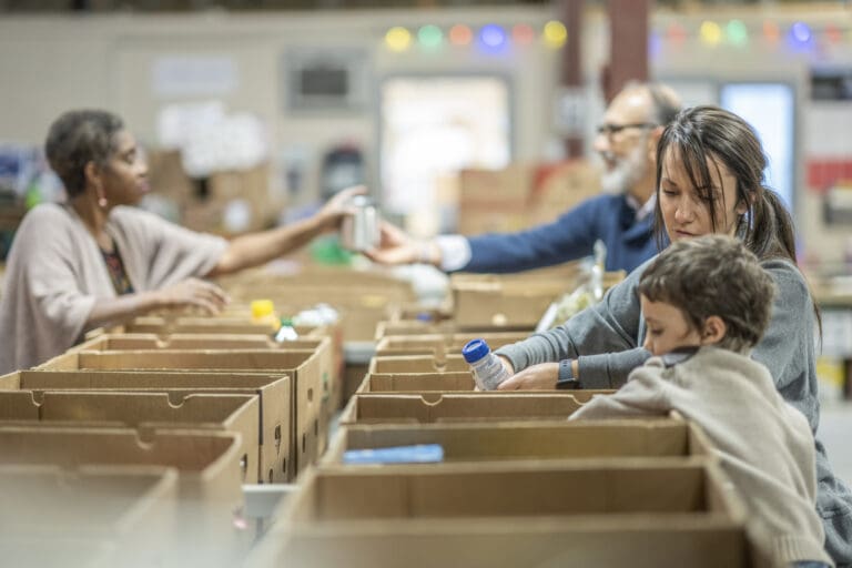 Homeless shelter showing a small group of people donating their time distributing non-perishable goods to families and people in need.