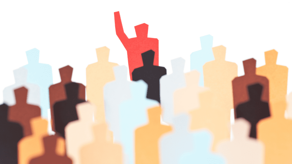 colored paper cut to resemble people, in the middle is a red person with arm raised